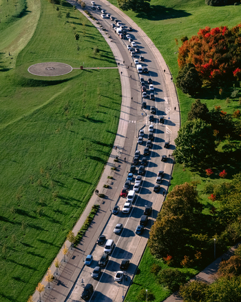 Aerial view of a winding road filled with heavy traffic surrounded by lush green parkland and autumn colored trees in Vilnius Vilnius County Lithuania.