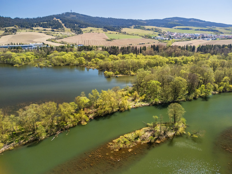 Aerial view of Biela Orava river with lush green islands and forested hills under a clear blue sky in Namestovo Zilinsky kraj Slovakia. Aerial view of Biela Orava river with lush green islands and forested hills under a clear blue sky in Namestovo Zilinsky kraj Slovakia.