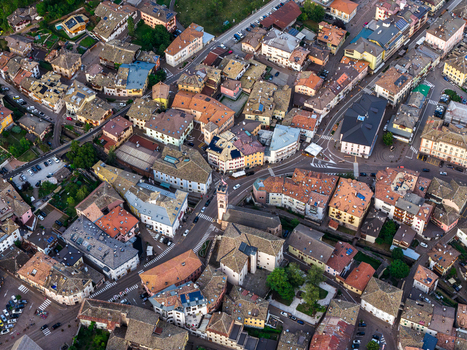 Aerial view of Fiemme Valley showing a dense cluster of historic buildings with terracotta rooftops narrow streets and mountain architecture in Trentino Alto Adige Italy.