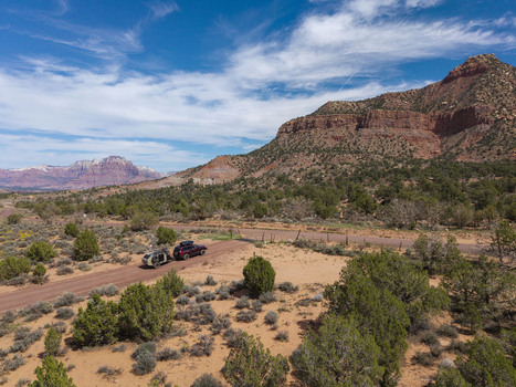 Aerial view of an SUV pulling a teardrop camper trailer on a dirt road on Gooseberry Mesa with Zion National Park in the background in Hurricane Utah United States. Aerial view of an SUV pulling a teardrop camper trailer on a dirt road on Gooseberry Mesa with Zion National Park in the background in Hurricane Utah United States.