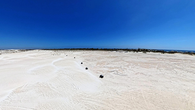 Aerial view of Lancelin Sand Dunes with quad bikes driving across the vast white sand landscape under a clear blue sky in Lancelin Western Australia Australia. Aerial view of Lancelin Sand Dunes with quad bikes driving across the vast white sand landscape under a clear blue sky in Lancelin Western Australia Australia.