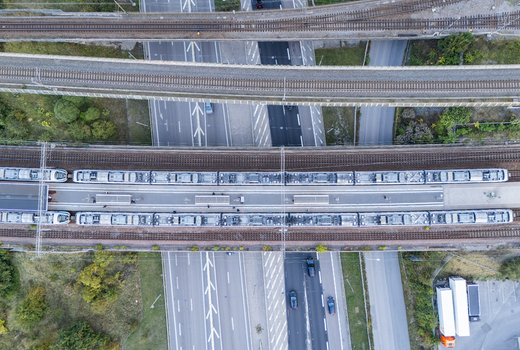 Aerial view of a commuter train on tracks crossing over a busy highway with cars and trucks in Stockholm Stockholm County Sweden.