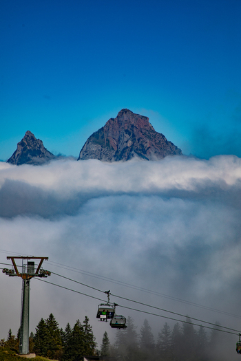 View of the Swiss Alps rising above a thick layer of clouds with a cable car system in the foreground in Airolo Ticino Switzerland. View of the Swiss Alps rising above a thick layer of clouds with a cable car system in the foreground in Airolo Ticino Switzerland.