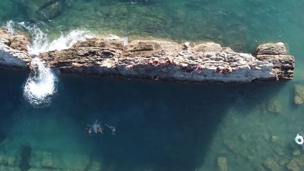 Aerial view of people jumping from rocks into the turquoise sea Italy. Aerial view of people jumping from rocks into the turquoise sea Italy.