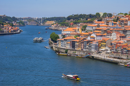 Aerial view of the Douro River winding through the terracotta rooftops and ancient buildings towards the Arrábida Bridge Porto Porto District Portugal. Aerial view of the Douro River winding through the terracotta rooftops and ancient buildings towards the Arrábida Bridge Porto Porto District Portugal.