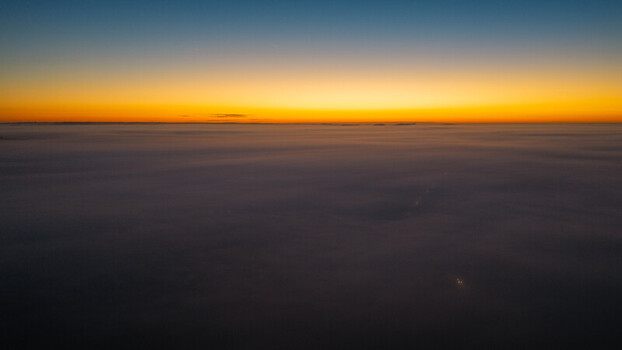 Aerial view of a vast sea of thick fog covering the landscape during a vibrant sunset with a glowing orange horizon. Salisbury England United Kingdom. Aerial view of a vast sea of thick fog covering the landscape during a vibrant sunset with a glowing orange horizon. Salisbury England United Kingdom.