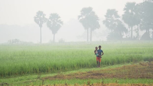 View of children walking through a misty field in Bogura Bangladesh.