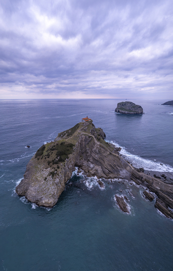 Aerial view of San Juan de Gaztelugatxe a historic hermitage on a rocky islet with a winding stone bridge surrounded by the Cantabrian Sea in Gaztelugatxeko Doniene Euskadi Spain.