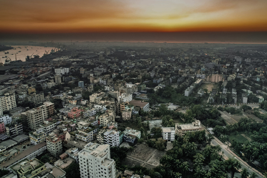 Chattogram Bangladesh 06 January 2022 Aerial view of the dense urban cityscape of Chattogram at sunset with residential buildings industrial port areas and lush greenery.