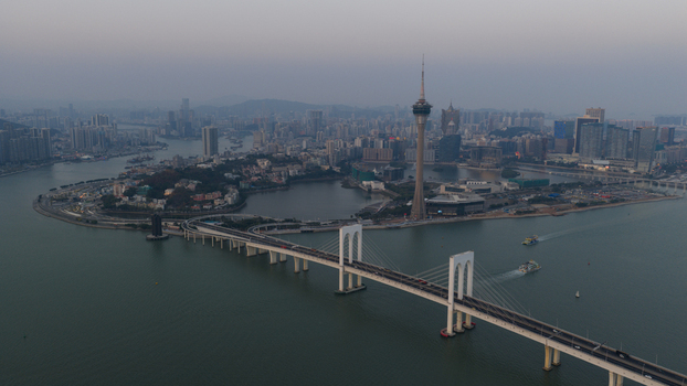 Aerial view of the Macau Tower and Sai Van Bridge spanning the water with the city skyline under a hazy sky Macau Macao. Aerial view of the Macau Tower and Sai Van Bridge spanning the water with the city skyline under a hazy sky Macau Macao.