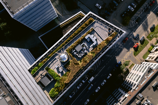Aerial view of a modern building with a green roof featuring vegetation and HVAC systems situated next to a road with cars in Vilnius Vilnius County Lithuania.