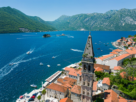 Aerial view of the Church of St. Nicholas bell tower terracotta rooftops and the blue waters of the Bay of Kotor in Perast Kotor Municipality Montenegro. Aerial view of the Church of St. Nicholas bell tower terracotta rooftops and the blue waters of the Bay of Kotor in Perast Kotor Municipality Montenegro.