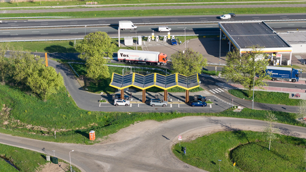 Bant Netherlands 23 April 2026 Aerial view of the Fastned Charging Station with its iconic yellow solar roof electric cars charging and a busy highway with trucks in the background. Bant Netherlands 23 April 2026 Aerial view of the Fastned Charging Station with its iconic yellow solar roof electric cars charging and a busy highway with trucks in the background.