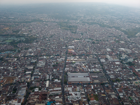 Aerial view of the dense urban landscape of Malang featuring numerous residential rooftops commercial buildings and intersecting streets in Malang East Java Indonesia.