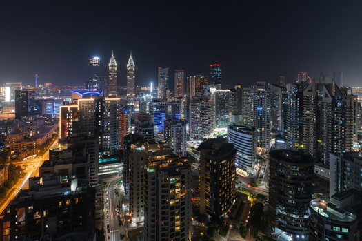 View of a glittering skyline ablaze with light as skyscrapers pierce the night sky casting a warm glow over the vibrant city Dubai Dubai United Arab Emirates. View of a glittering skyline ablaze with light as skyscrapers pierce the night sky casting a warm glow over the vibrant city Dubai Dubai United Arab Emirates.