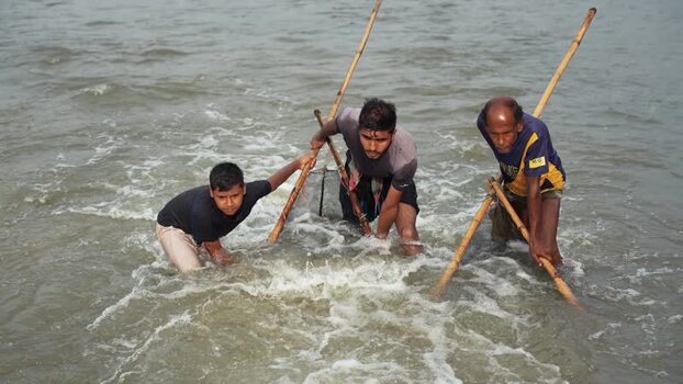 View of fishermen using bamboo poles in a river Bangladesh.