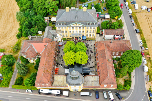 Aerial view of Schloss Jagersburg baroque palace featuring a central courtyard with green trees and people gathered during an event in Eggolsheim Bayern Germany. Aerial view of Schloss Jagersburg baroque palace featuring a central courtyard with green trees and people gathered during an event in Eggolsheim Bayern Germany.