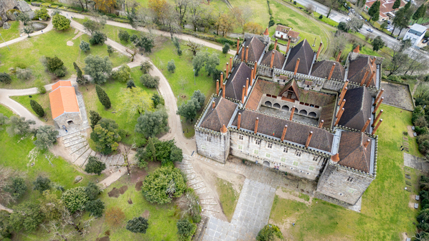 Aerial view of the Palace Duques de Braganca with its distinctive stone chimneys and medieval architecture surrounded by lush green parkland in Guimaraes Braga Portugal.