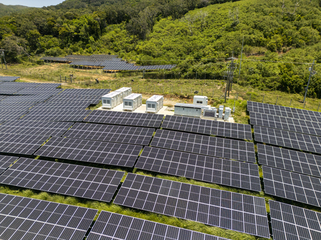 Aerial view of a large solar panel array surrounded by dense tropical forest and lush green hills Guanaja Bay Islands Department Honduras.