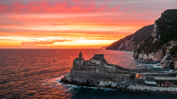 Aerial view of Chiesa di San Pietro on a rocky cliff overlooking the sea during a vibrant sunset in Portovenere Liguria Italy. Aerial view of Chiesa di San Pietro on a rocky cliff overlooking the sea during a vibrant sunset in Portovenere Liguria Italy.