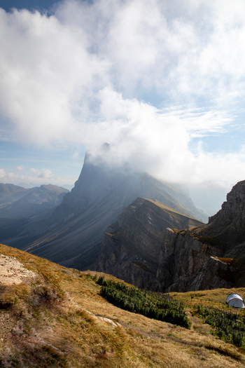 View of the rugged Dolomites mountain peaks partially covered by white clouds under a blue sky in Rocca Pietore Veneto Italy. View of the rugged Dolomites mountain peaks partially covered by white clouds under a blue sky in Rocca Pietore Veneto Italy.