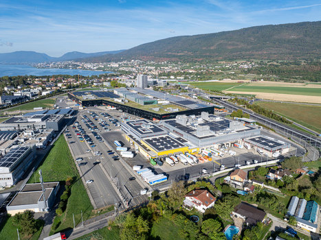 Aerial view of Marin Centre shopping complex featuring large flat rooftops with solar panels loading docks with trucks and parking lots in Latena Neuchatel Switzerland. Aerial view of Marin Centre shopping complex featuring large flat rooftops with solar panels loading docks with trucks and parking lots in Latena Neuchatel Switzerland.