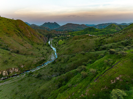 Aerial view of the lush green Aravalli hills surrounding a winding river in Udaipur Rajasthan India.