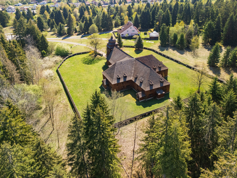 Aerial view of the Wooden Articular Church of Svaty Kriz with its dark shingle roof and green lawn surrounded by a dense forest in Svaty Kriz Zilinsky kraj Slovakia.