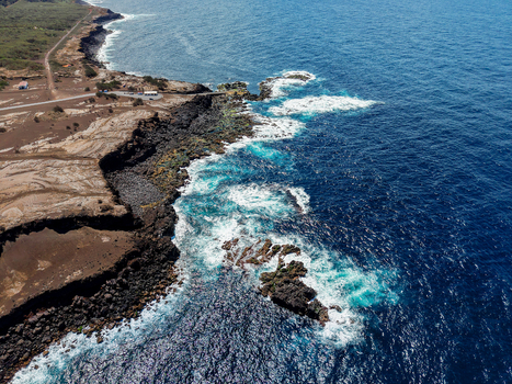 Aerial view of the rugged coastline where the dark volcanic cliffs meet the foamy turquoise sea Capelo A&ccedil;ores Portugal.