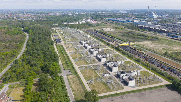 Aerial view of a large electrical substation with high voltage power lines and concrete structures surrounded by forest and industrial zones in Velsen Noord North Holland Netherlands.