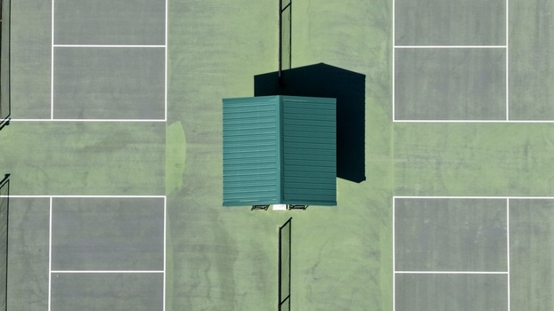 Aerial view of tennis courts with a green structure and shadows cast on the court surface in St. Johns County Florida United States. Aerial view of tennis courts with a green structure and shadows cast on the court surface in St. Johns County Florida United States.