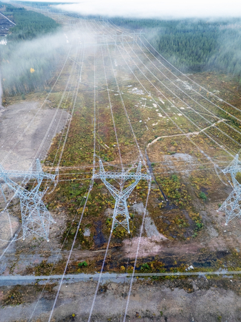 Aerial view of high voltage power lines and transmission towers stretching through a misty forest landscape in Muhos North Ostrobothnia Finland.