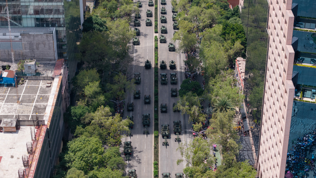 Aerial view of a military parade with armored vehicles moving along a tree lined avenue in Mexico City Mexico City Mexico.