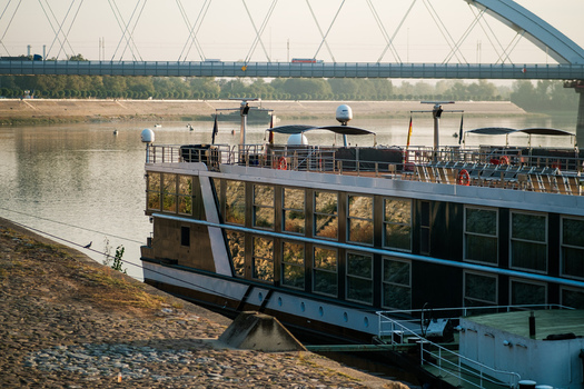View of a river cruise ship docked on the Danube river with the Zezelj Bridge in the background in Novi Sad Vojvodina Serbia. View of a river cruise ship docked on the Danube river with the Zezelj Bridge in the background in Novi Sad Vojvodina Serbia.