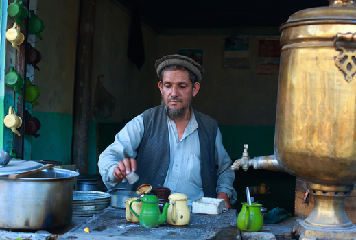 Chitral Khyber Pakhtunkhwa Pakistan 18 May 2013 View of a man preparing tea with a traditional brass samovar and colorful teapots in a local shop at the bazaar.
