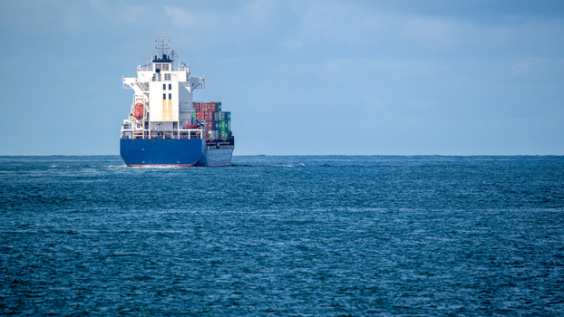 View of a large container ship carrying colorful cargo across the calm blue waters of the Atlantic Ocean under a cloudy sky Lisbon Lisbon Portugal. View of a large container ship carrying colorful cargo across the calm blue waters of the Atlantic Ocean under a cloudy sky Lisbon Lisbon Portugal.