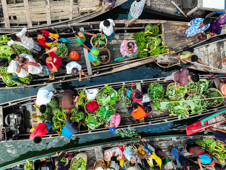 Rangamati Hill District Bangladesh 18 May 2024 Aerial view of Kaptai Lake with local farmers and traders on wooden boats transporting fresh bananas and green produce.
