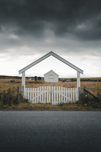 View of the white wooden gate framing the historic Flakstad Church in a grassy field under a dramatic cloudy sky in Ramberg Nordland Norway. View of the white wooden gate framing the historic Flakstad Church in a grassy field under a dramatic cloudy sky in Ramberg Nordland Norway.