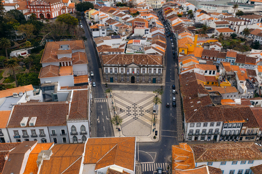 Aerial view of the historic city hall and Praca Velha with its patterned pavement surrounded by orange roofed houses in Angra do Heroismo Azores Portugal.