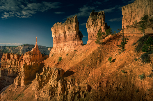 View of Bryce Canyon National Park with its iconic orange hoodoos rugged rock formations and scattered pine trees under a clear blue sky in Utah United States.