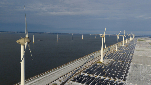 Aerial view of modern wind turbines and rows of solar panels along a coastal dike under a cloudy winter sky in Espel Flevoland Netherlands. Aerial view of modern wind turbines and rows of solar panels along a coastal dike under a cloudy winter sky in Espel Flevoland Netherlands.