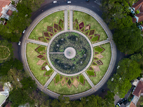 Aerial view of Alun Alun Tugu Malang featuring a circular park with a central pond fountains and lotus shaped garden beds surrounded by lush trees in Malang East Java Indonesia.