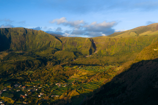 Aerial view of Poco da Ribeira do Ferreiro waterfalls cascading down steep green cliffs overlooking the rural landscape and fields of Fajazinha Azores Portugal. Aerial view of Poco da Ribeira do Ferreiro waterfalls cascading down steep green cliffs overlooking the rural landscape and fields of Fajazinha Azores Portugal.