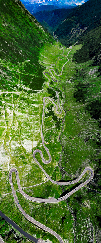 Aerial view of the winding Transfagarasan mountain road cutting through the lush green slopes of the Carpathian Mountains Curtea de Arges Judetul Arges Romania. Aerial view of the winding Transfagarasan mountain road cutting through the lush green slopes of the Carpathian Mountains Curtea de Arges Judetul Arges Romania.