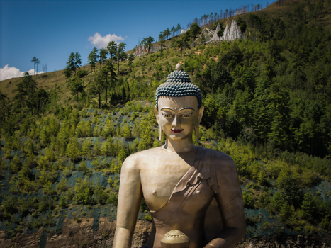 Aerial view of the golden Great Buddha Dordenma statue amidst the lush green hills and clear blue skies of the mountains Thimphu Bhutan.