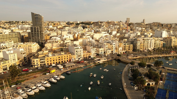 Aerial view of Spinola Bay in St. Julian s with numerous yachts and boats moored in the harbor surrounded by dense urban architecture and buildings in Malta. Aerial view of Spinola Bay in St. Julian s with numerous yachts and boats moored in the harbor surrounded by dense urban architecture and buildings in Malta.