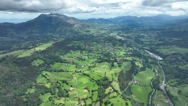 Aerial view of lush green valley and village with winding roads Spain.