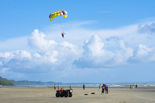 Cox s Bazar Bangladesh 18 August 2023 Aerial view of a vibrant parasail against the backdrop of the beach and the vast blue sky dotted with fluffy white clouds. Cox s Bazar Bangladesh 18 August 2023 Aerial view of a vibrant parasail against the backdrop of the beach and the vast blue sky dotted with fluffy white clouds.