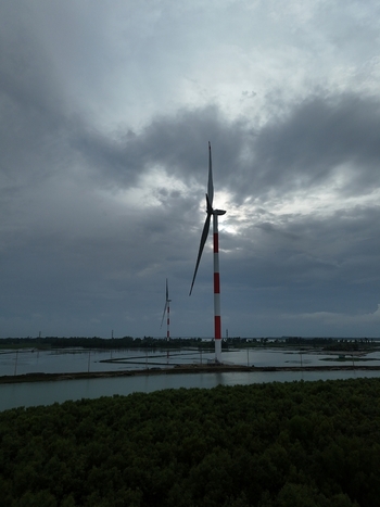 Aerial view of Khurushkul wind power plant with red and white turbines standing in the flooded landscape under a cloudy sky in Cox s Bazar Chittagong Division Bangladesh. Aerial view of Khurushkul wind power plant with red and white turbines standing in the flooded landscape under a cloudy sky in Cox s Bazar Chittagong Division Bangladesh.