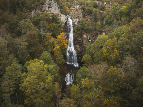 Aerial view of the cascading waterfall plunging through the dense forest a symphony of verdant greens and autumn golds Pont de Montvert Sud Mont Lozère Occitanie France. Aerial view of the cascading waterfall plunging through the dense forest a symphony of verdant greens and autumn golds Pont de Montvert Sud Mont Lozère Occitanie France.
